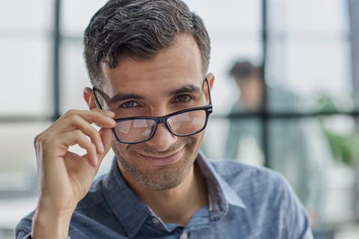 IT guy adjusting glasses in a modern new office