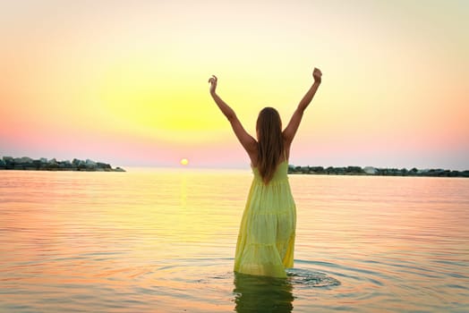 Young woman at sea under sunrise light.