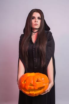 Jack o Lantern Halloween pumpkin grinning in the most evil fashion in woman's hands