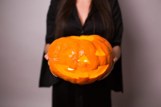 Jack o Lantern Halloween pumpkin grinning in the most evil fashion in woman's hands