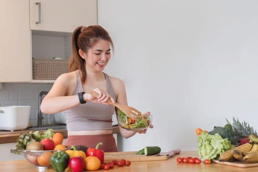 Young athletic woman is preparing a healthy organic vegetable salad in a modern kitchen at home..