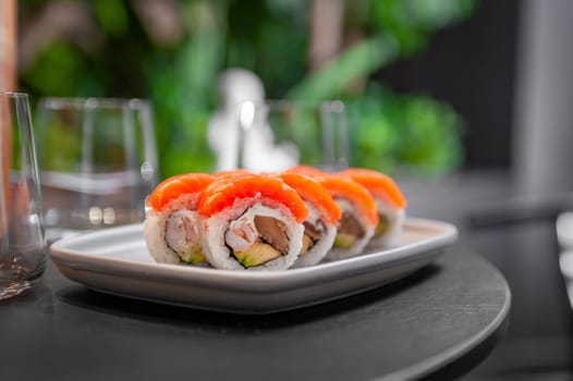 Sushi roll with salmon, shrimp, avocado and cream cheese on a plate close-up. High quality photo