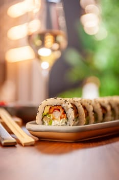 Sushi roll with cream cheese, sesame seeds and green flying fish caviar on a plate close-up. High quality photo