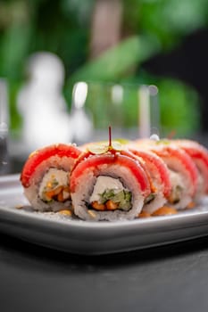 Sushi roll with tuna, cream cheese, cucumber and curry sauce on a plate close-up. High quality photo