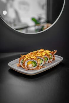 Sushi roll with tuna flakes, tempura shrimp, mango and cucumber on a plate close-up. High quality photo