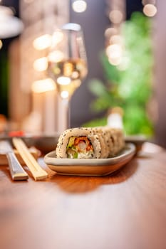 Sushi roll with cream cheese, sesame seeds and green flying fish caviar on a plate close-up. High quality photo