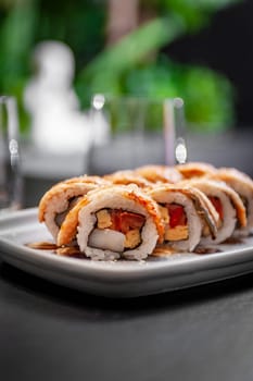 Sushi roll with eel, scallop, tomato and tamago on a plate close-up. High quality photo