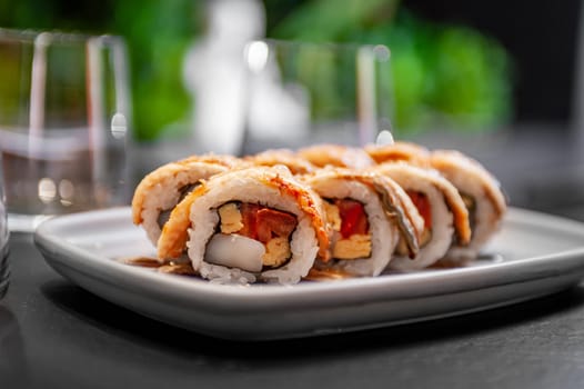 Sushi roll with eel, scallop, tomato and tamago on a plate close-up. High quality photo