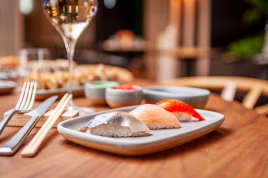 Nigiri set: mackerel, sea bass, salmon on a plate on a table in a sushi bar on a plate close-up. High quality photo