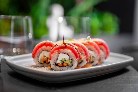 Sushi roll with tuna, cream cheese, cucumber and curry sauce on a plate close-up. High quality photo