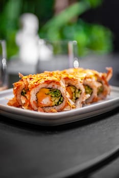 Sushi roll with tuna flakes, tempura shrimp, mango and cucumber on a plate close-up. High quality photo