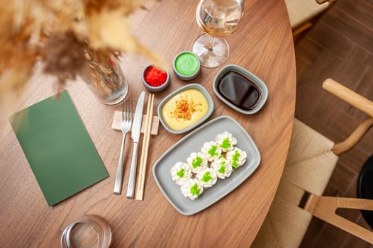 Sushi roll with cream cheese, sesame seeds and green flying fish caviar on a plate close-up. High quality photo