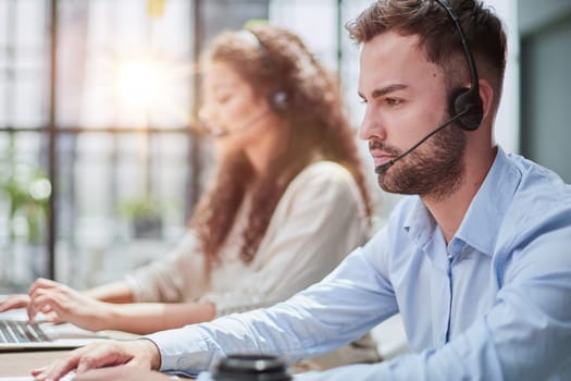 Handsome male customer service agent working in call center office as a telemarketer.