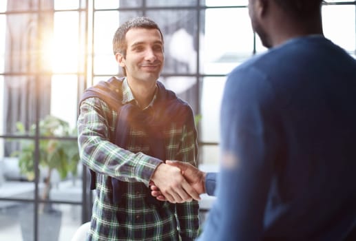 Diverse male colleagues in modern office corridor, young african american and caucasian business people discussing common project work, meeting in company work