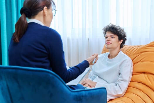 Young guy in therapy session discussing his emotional problems with female psychotherapist. Psychological assistance services, mental health, counseling, support, psychotherapy, psychology concept