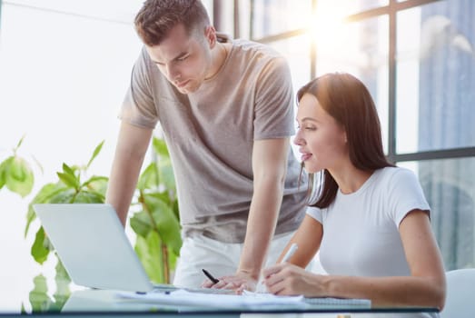 male ceo executive manager mentor giving consultation on financial operations to female colleague intern using laptop sitting in modern office