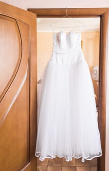 The perfect wedding dress on a hanger in the room of bride.