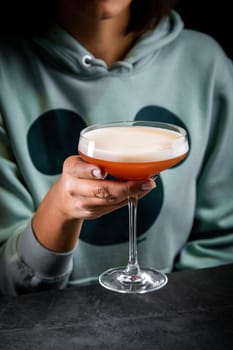 iced latte with foam in a martini glass on a dark background side view