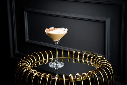 iced latte with foam in a martini glass on a dark background side view