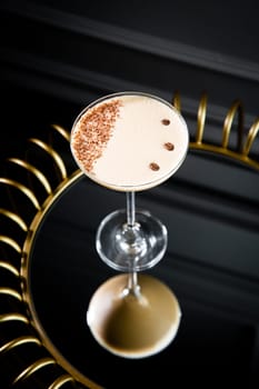 iced latte with foam in a martini glass on a dark background side view