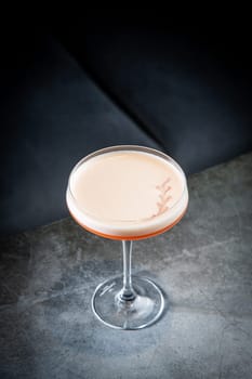 iced latte with foam in a martini glass on a dark background side view