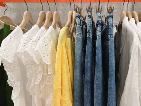 Blouses, sweaters, jeans hang on a hanger at the store
