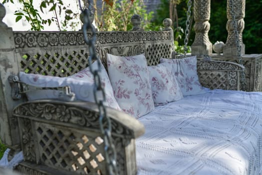 Hanging sofa-swing with pillows and bedspread in garden