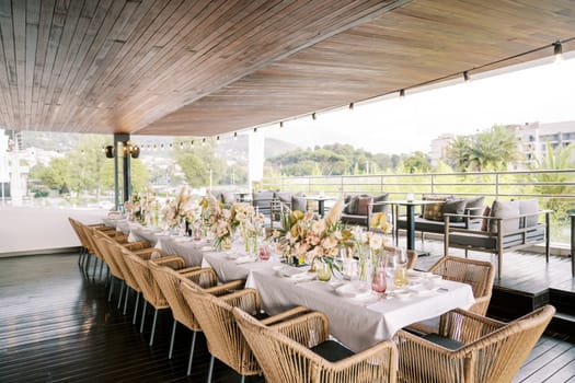 Long festive table on the restaurant terrace with panoramic views of the green park and houses. High quality photo