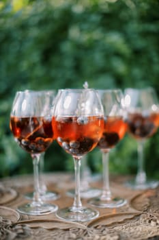 Cocktails with wine and floating blueberries stand on a wooden table in the garden. High quality photo