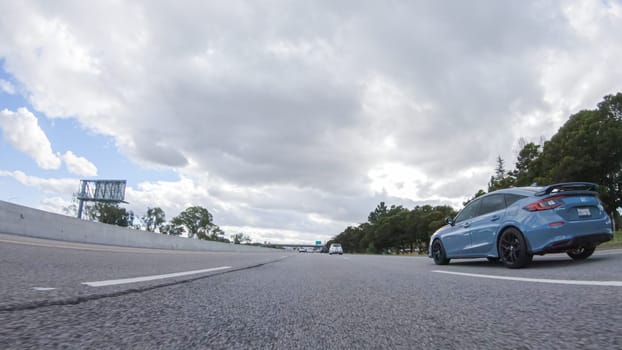 Santa Maria, California, USA-December 6, 2022-On a cloudy winter day, a car smoothly travels along Highway 101 near Santa Maria, California, under a cloudy sky, surrounded by a blend of greenery and golden hues.