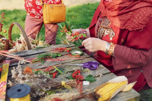A woman picking a bouquet of dried flowers and red berries
