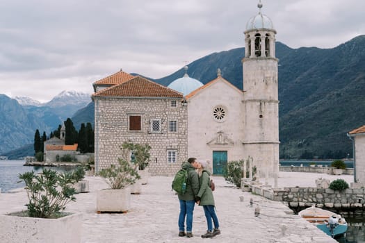 Man and woman kiss on the island of Gospa od Skrpjela, holding hands. Montenegro. High quality photo