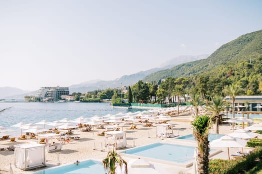 Luxurious sandy beach with sun loungers and white parasols at the One and Only Hotel. Portonovi, Montenegro. High quality photo