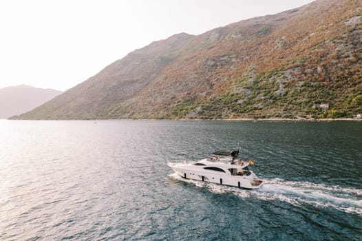 Motor single-deck yacht sails along the sea along the mountain coast. High quality photo