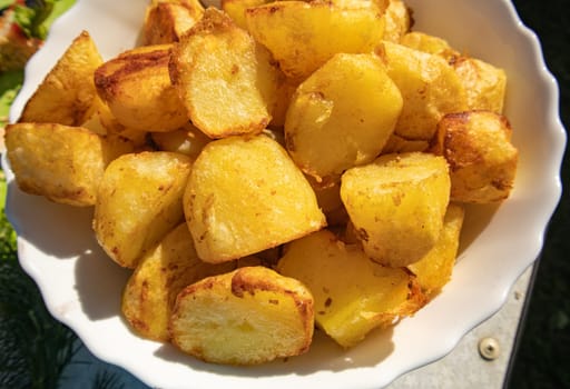 Potatoes fried in a frying pan close-up, lying on a white plate, Horizontal view from above, food background.