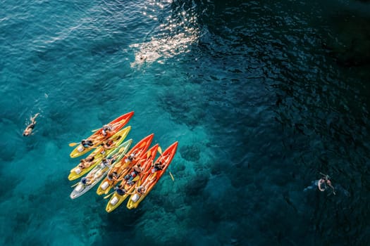 Tourists swim in the turquoise sea near a team of kayakers in kayaks. Drone. High quality photo