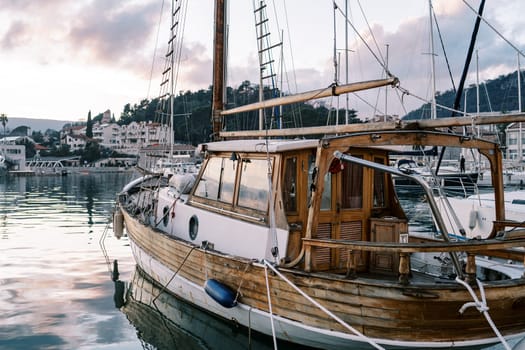 Wooden sailing yacht moored at the pier at the foot of the mountains at sunset. High quality photo