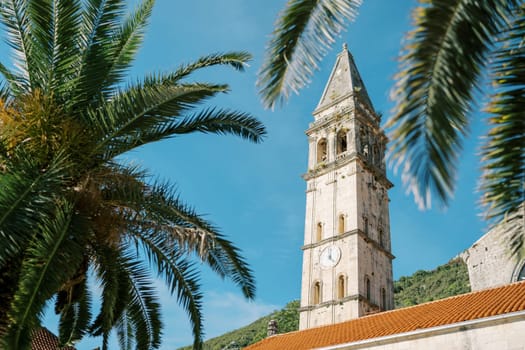 View through the branches of a tree to the bell tower of the Church of St. Nicholas in Perast. Montenegro. High quality photo