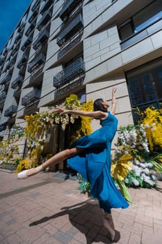 Beautiful Asian ballerina dances against the background of a building decorated with flowers. Vertical photo