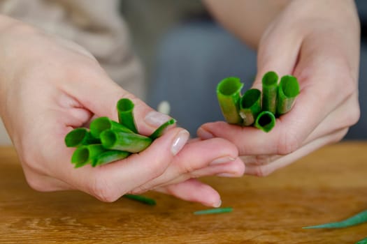 The process of preparing salad. A woman's hand chops a green onion close-up. Salad is used as a side dish for meals. High quality photo.