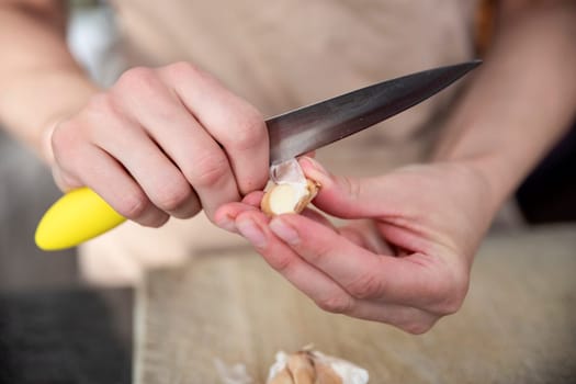 A woman cuts garlic with a knife close-up. Cutting garlic for salad or as an aromatic spice for meat. High quality photo