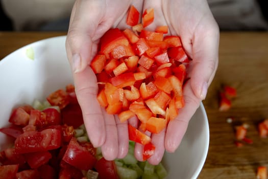 A woman's hands sprinkles small pieces of paprika close-up. Prepare salad as a side dish for the main dish. High quality photo