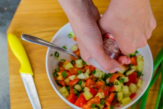 The process of preparing salad. Close-up of a woman's hands pouring salt into the salad to make the salad tastier. High quality photo