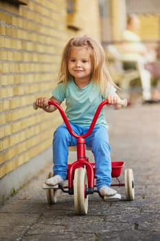 Charming blonde child rides a bicycle in Denmark.