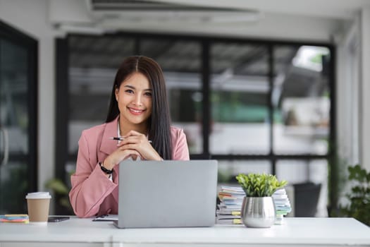 Businesswoman working with laptop computer while having a leisurely cup of coffee at the office in the morning..