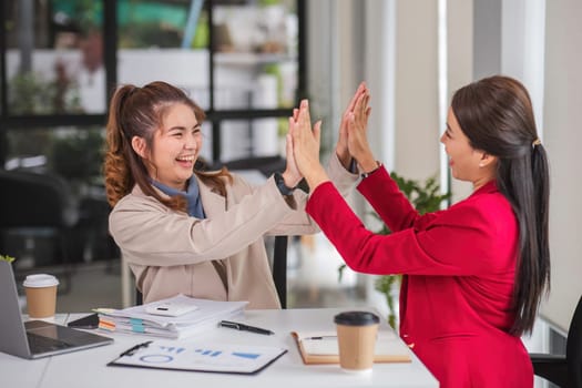 Two Asian businesswoman showing excited expression in front of laptop due to successful results..