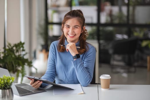 Portrait. Young successful businesswoman smiling cheerfully at her desk..