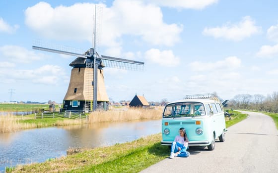 woman doing a road trip with an old vintage car in the Dutch flower bulb region with tulip fields during Spring in the Netherlands, women with a old camper van