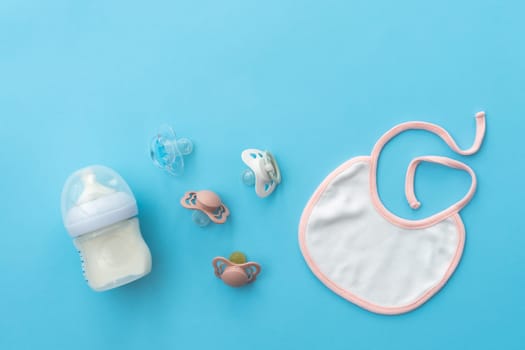 Key baby accessories and pacifiers are gracefully laid out on a soothing blue canvas, top view