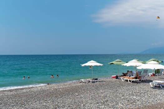The azure sea, the beach, vacationers sunbathing on the shore. Abkhazia, the city of Gagra - August 18, 2023.